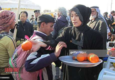 زن چینی در حال توزیع پرتقال بین زائرین اربعین